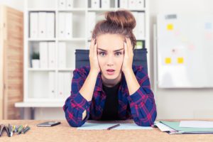 Young woman in checkered shirt is overwhelmed with amount of work she is supposed to do. Concept of overworking