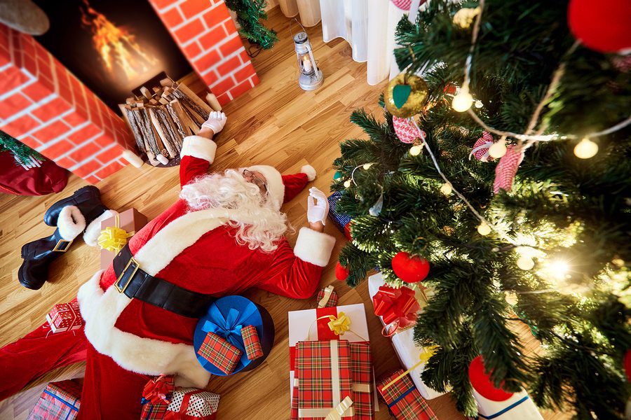 Santa Claus is sleeping tired drunk in a room near the fireplace and the Christmas tree after the New Year Christmas.